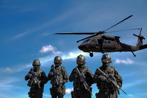 Four armed soldiers with a helicopter hovering overhead